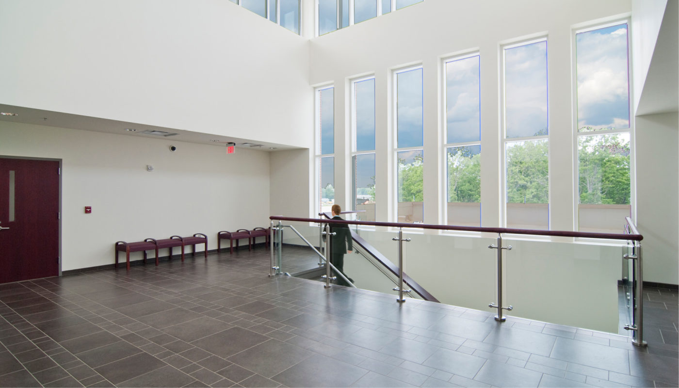 A hallway with large windows and a railing.