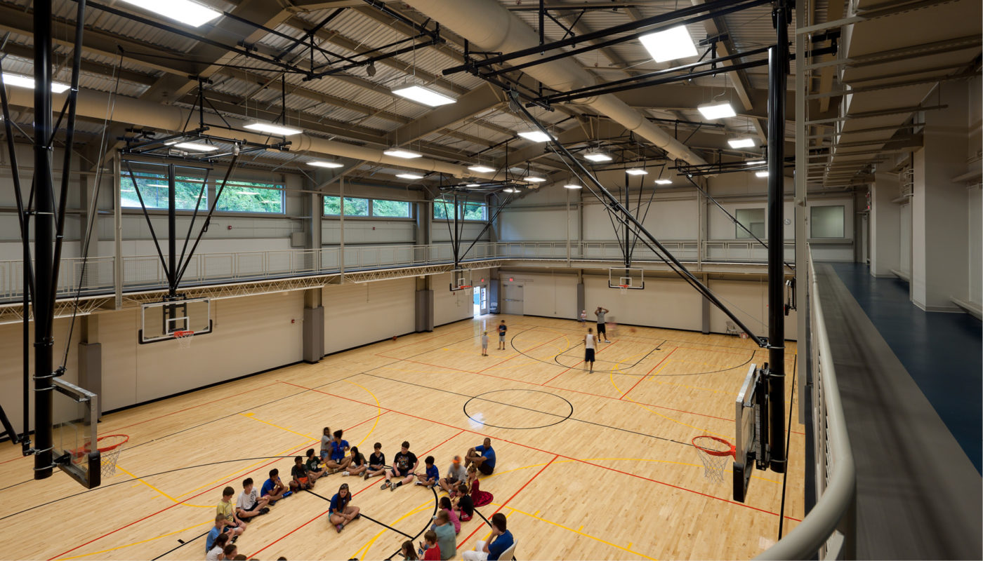 A basketball court in Baltimore, Maryland, at Roger Carter Community Center, crowded with many people participating in a game or practicing.