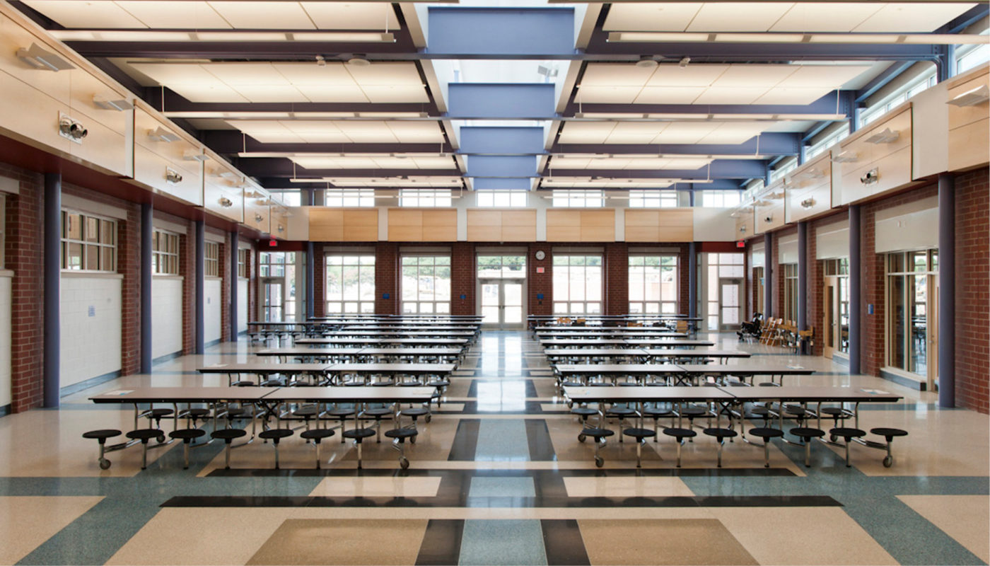 A large dining room with tables and chairs located at Crossroads PreK-8 School of Norfolk Public Schools.