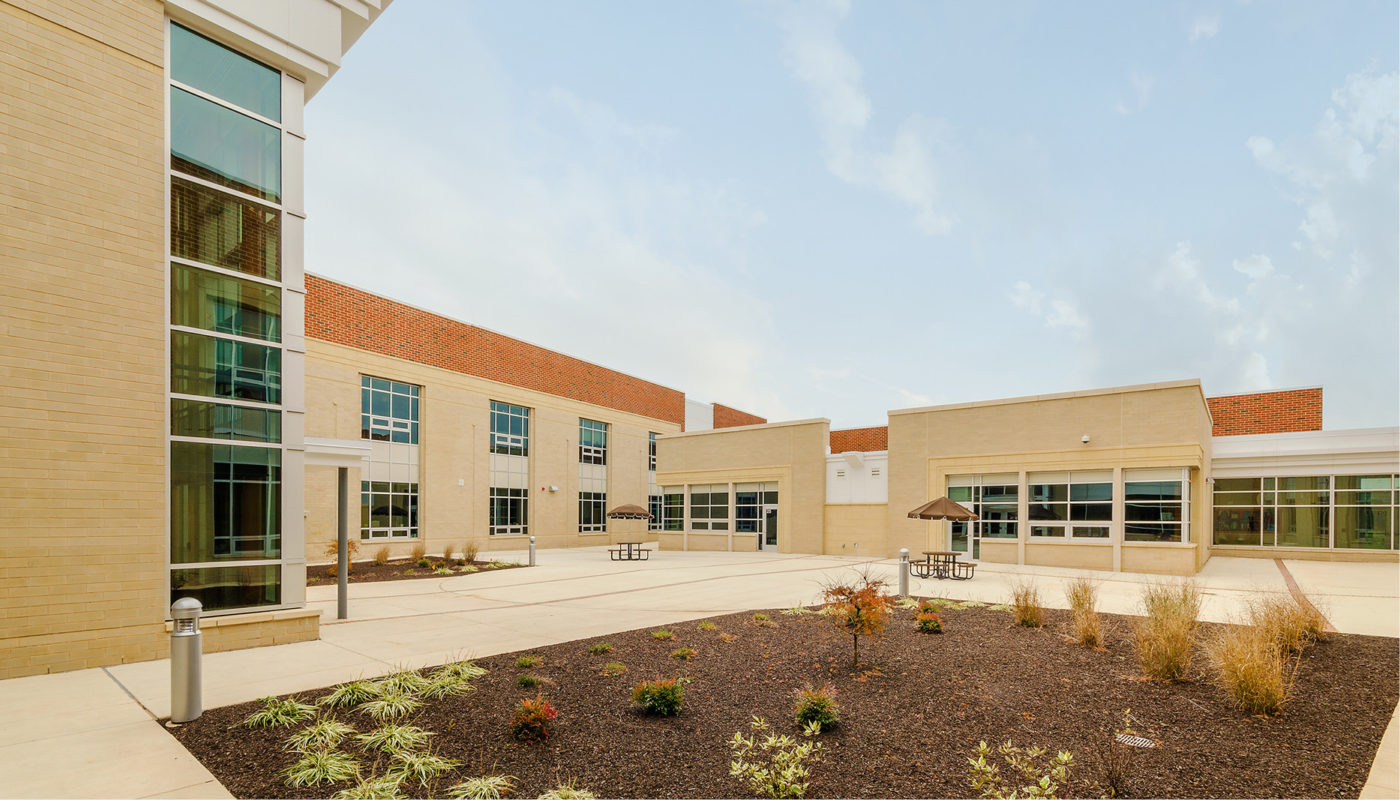 The exterior of a Prince William County Public Schools building with plants and trees.