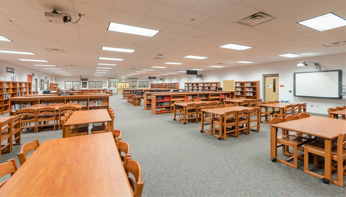 An empty library within Trailside Middle School, a part of Loudoun County Public Schools, furnished with tables and chairs.