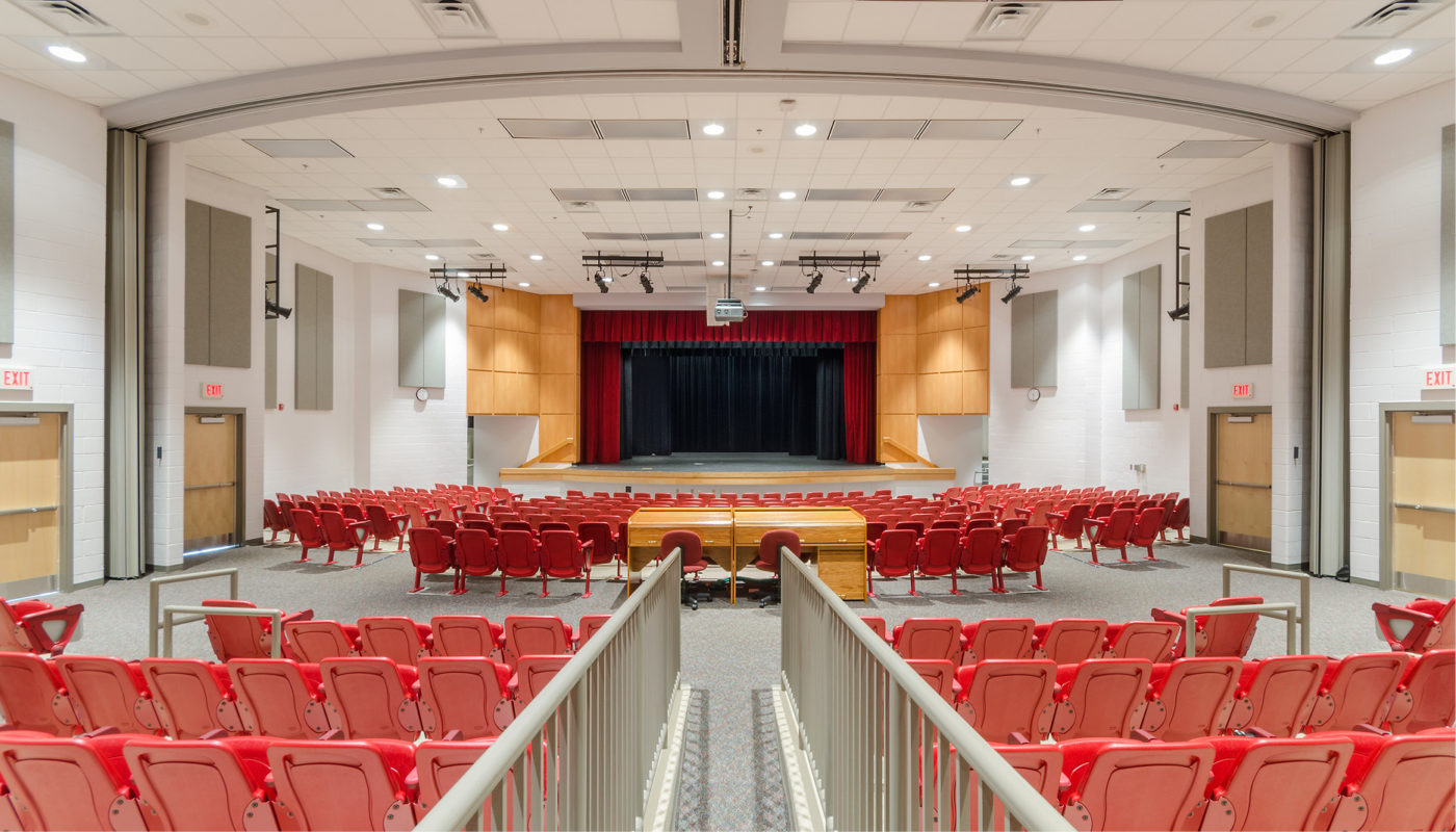 The Loudoun County Public Schools' Trailside Middle School houses a large auditorium with vibrant red chairs and a stage.