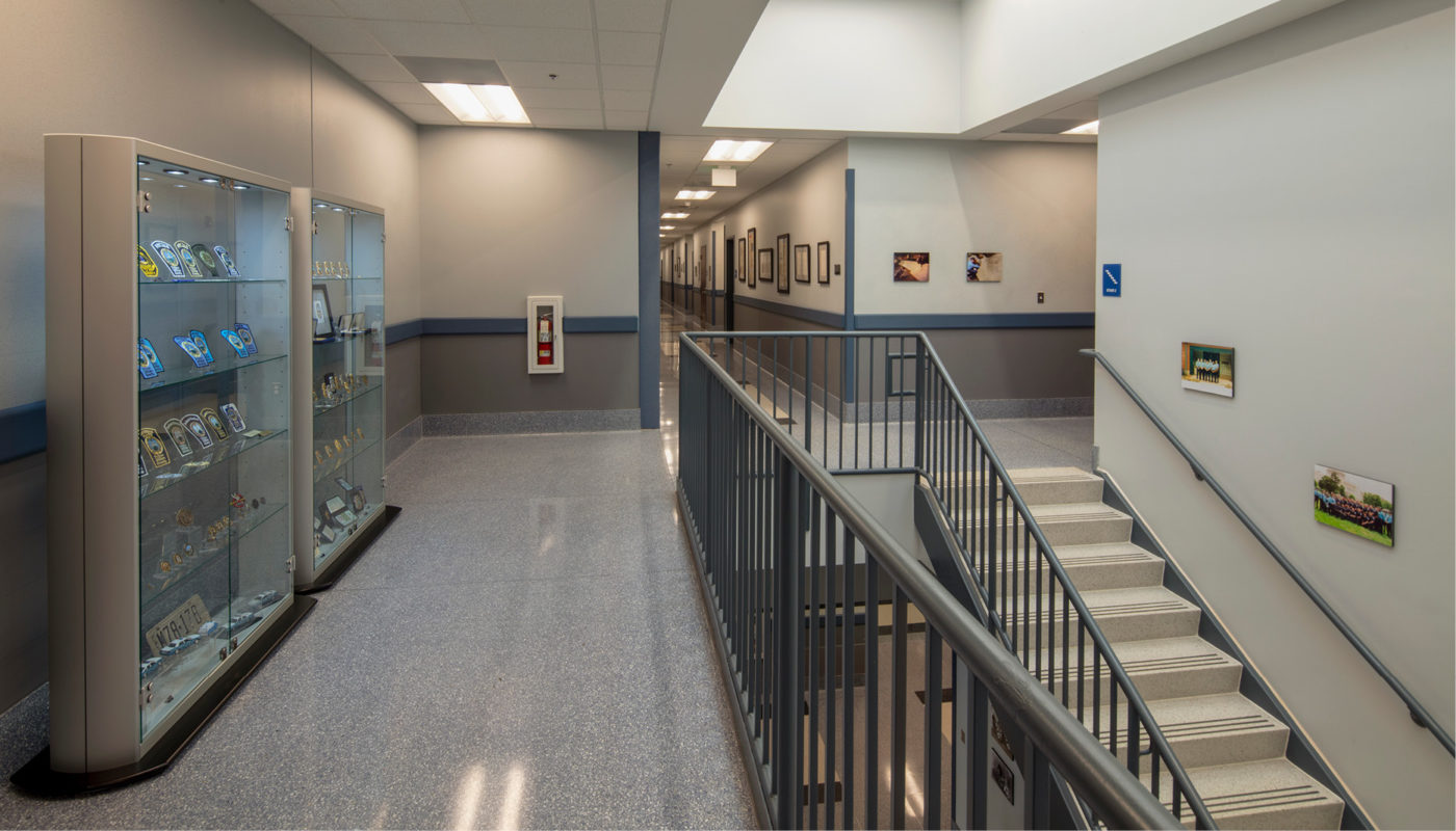 The Central District Police Station hallway features a prominent display case and a set of stairs.