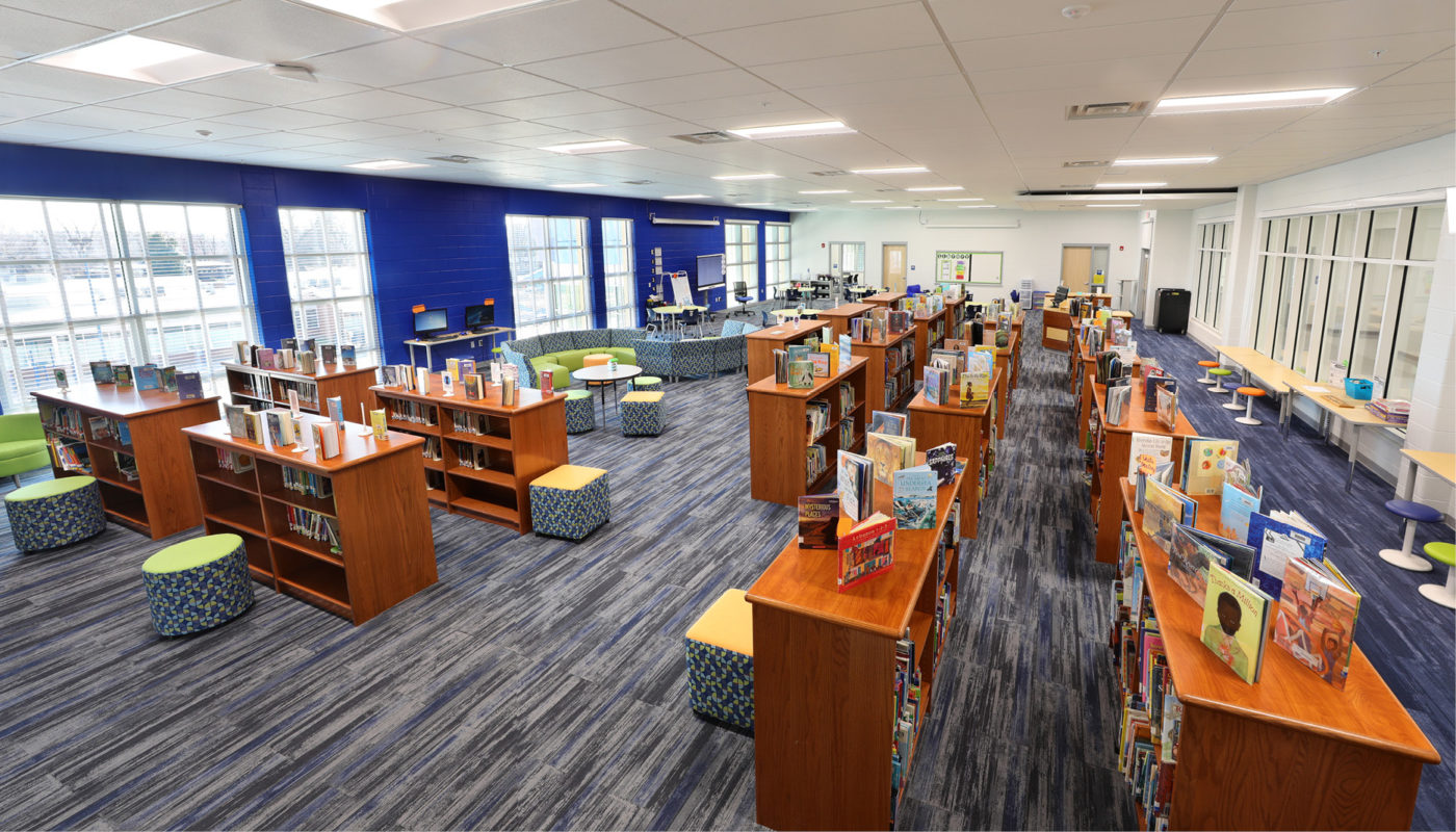 The interior of a K-8 school library in Alexandria City Public Schools, filled with many books on the shelves.