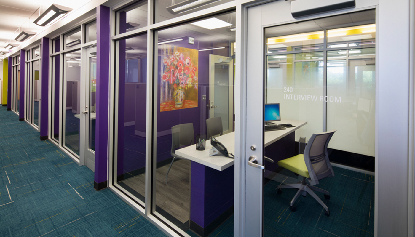 An office with glass doors and purple carpet.