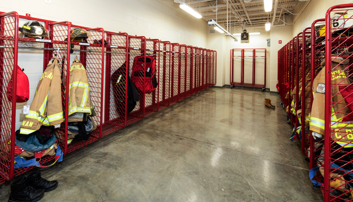 A firefighter's gear is hanging on a rack in a locker room.