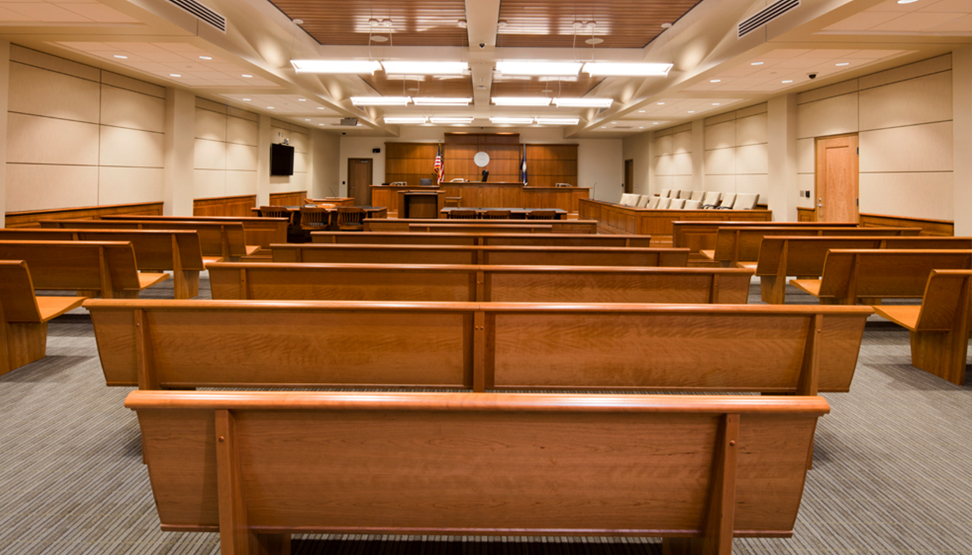 A courtroom with benches and a flag.