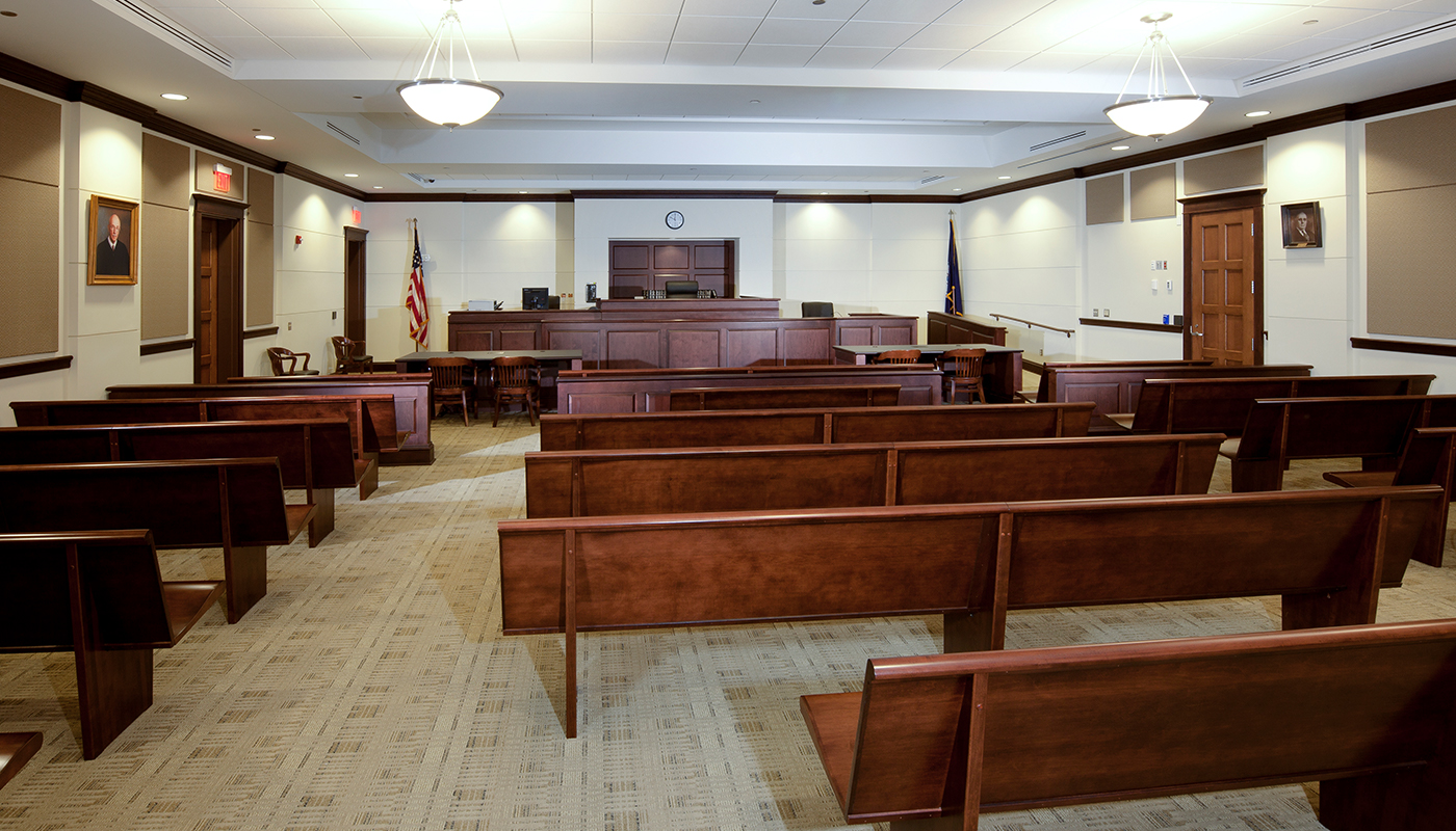 A courtroom with benches and a flag.