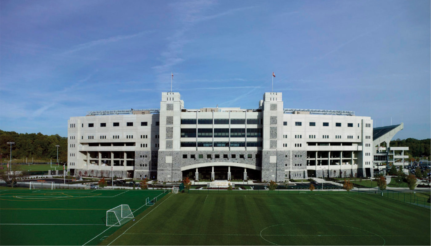 A large building with a soccer field in the background.
