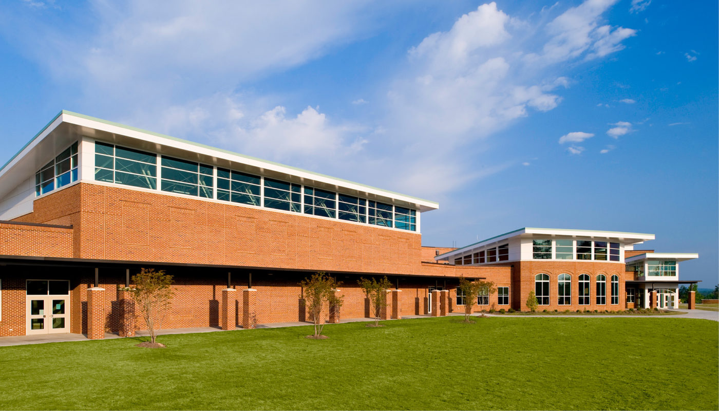 Carrboro High School, a large brick building with a grassy area in front of it, is part of the Chapel Hill-Carrboro City Schools.