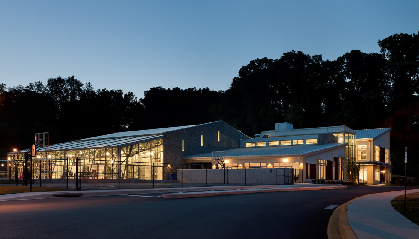 The Roger Carter Community Center, located in Baltimore, Maryland, is a stunning building featuring a glass facade that becomes even more mesmerizing at dusk.