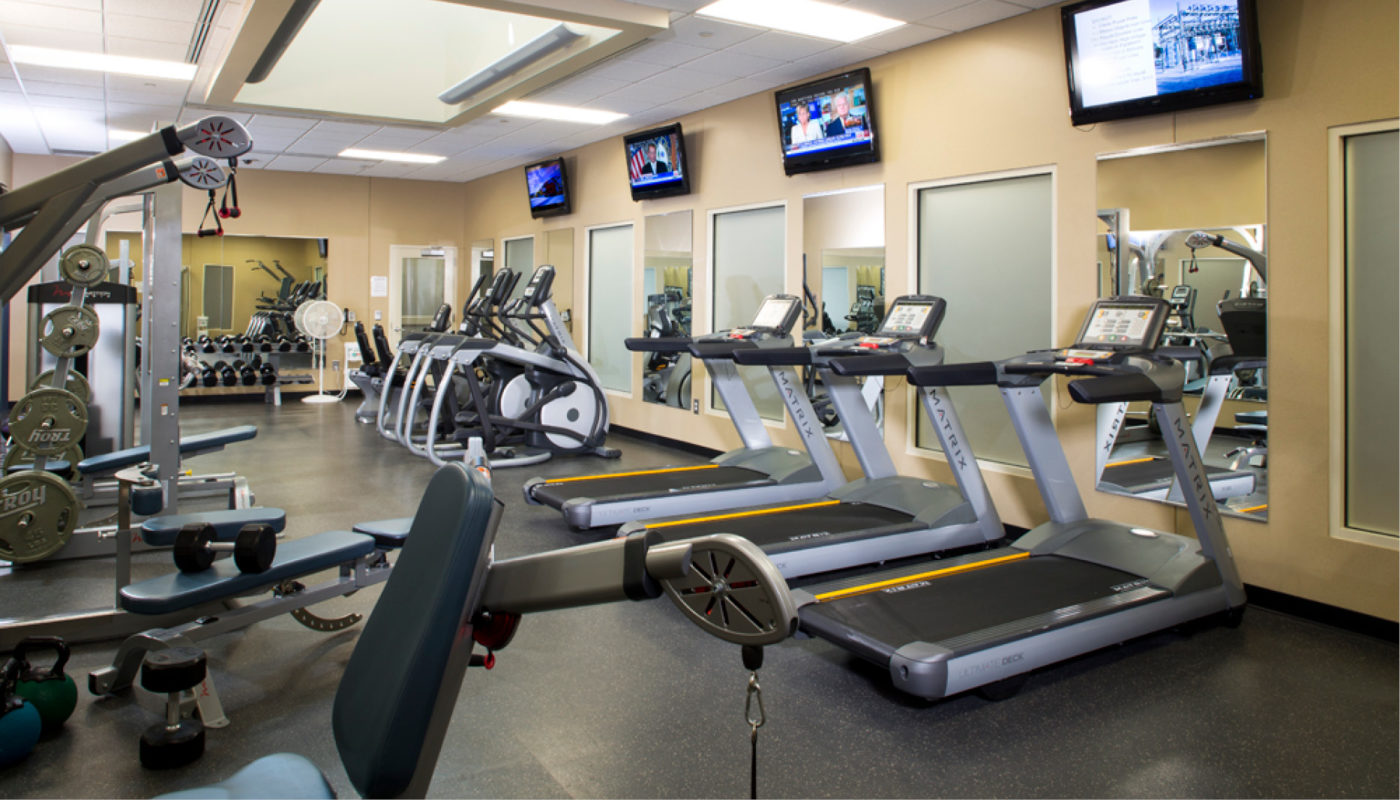 A gym with tread machines and tvs.