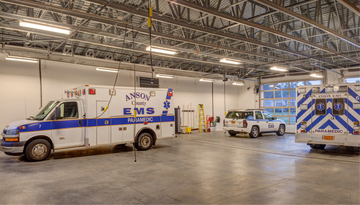 Two emergency services vehicles parked in a garage designed with an architectural touch.