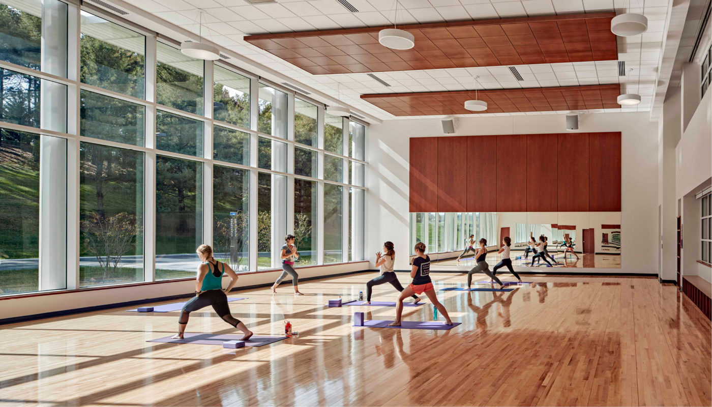 A group of people practicing yoga in a large gym.