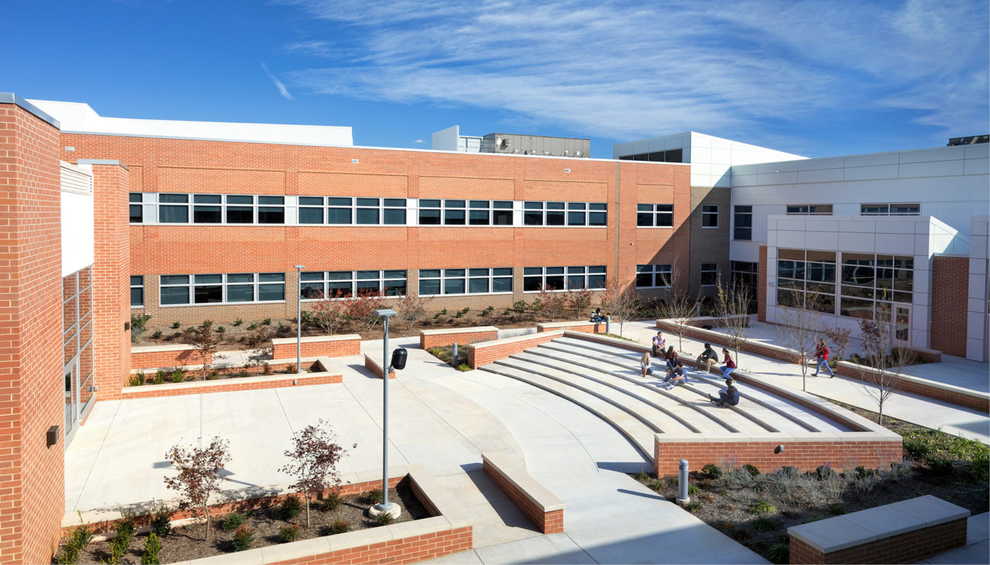 An image of a brick building with people walking around it, showcasing the beautiful architecture of Heritage High School.