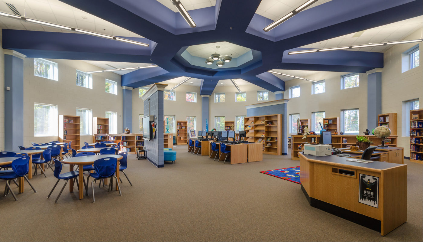 A library with a blue ceiling and tables and chairs.