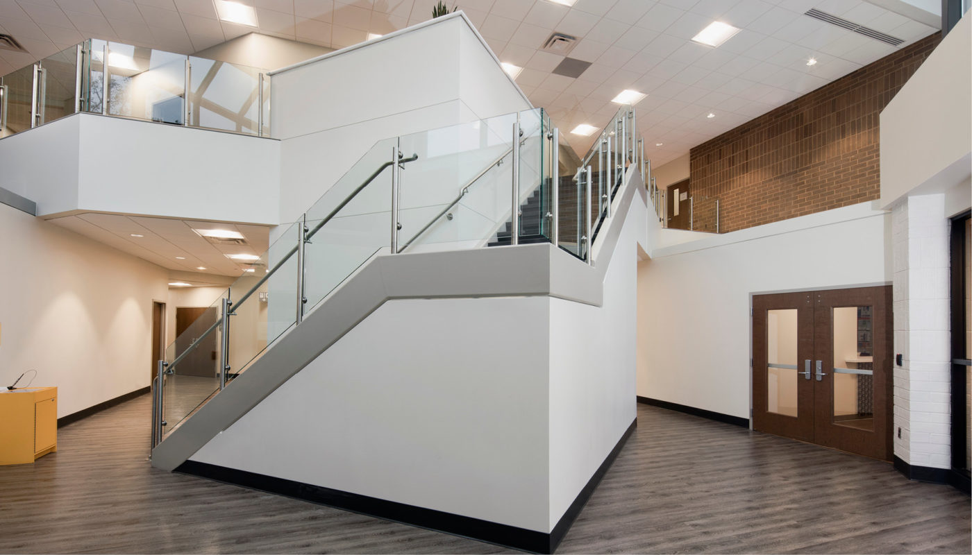 An office with a glass staircase and wooden floors.