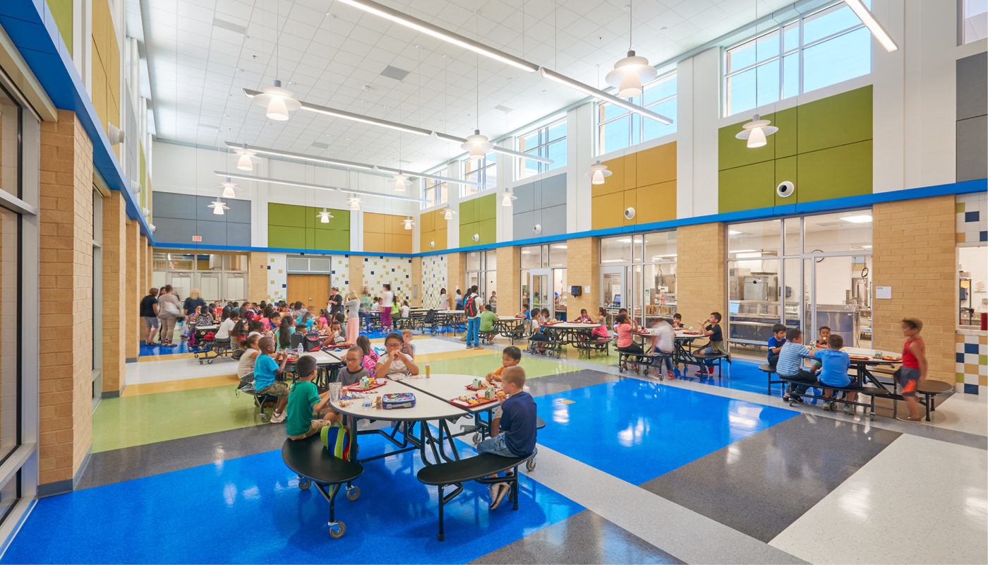 Baldwin Elementary, an Intermediate School in the Manassas City Public Schools district, has a bustling cafeteria filled with many people eating at tables.
