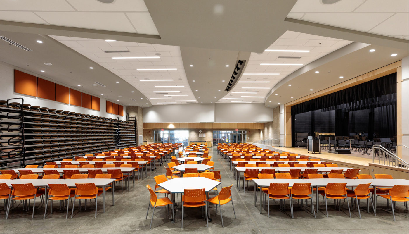 A large auditorium with orange chairs located in Powhatan Middle School, part of Powhatan County Public Schools.