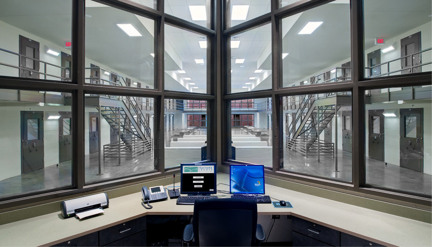 A computer desk in a Detention Center office with large windows.