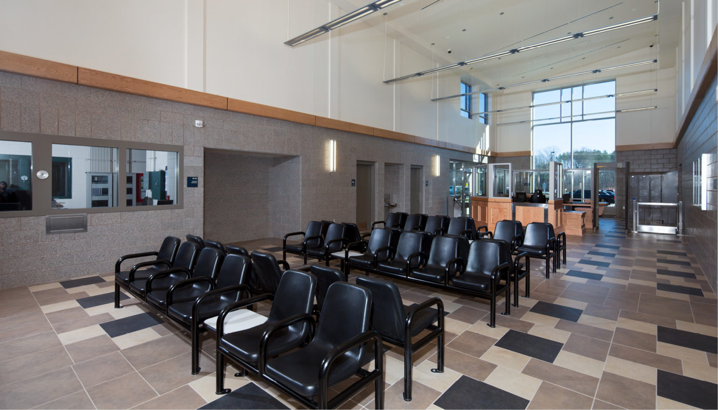 The Amherst Adult Detention Center features a spacious waiting room adorned with sleek black chairs and pristine tiled floors.