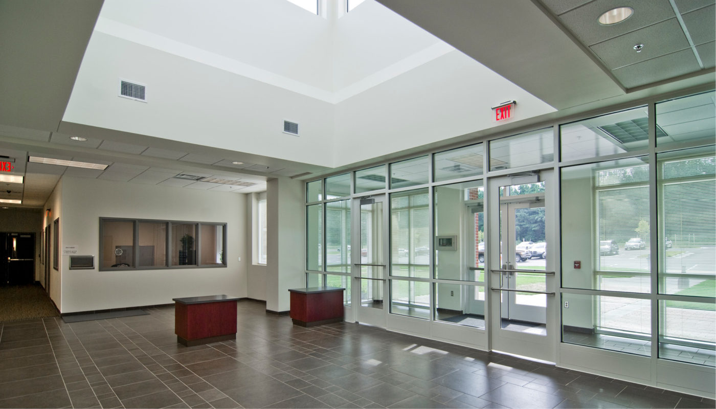 The Rockingham County Law Enforcement Center features a modern lobby adorned with elegant glass doors and a stunning skylight.