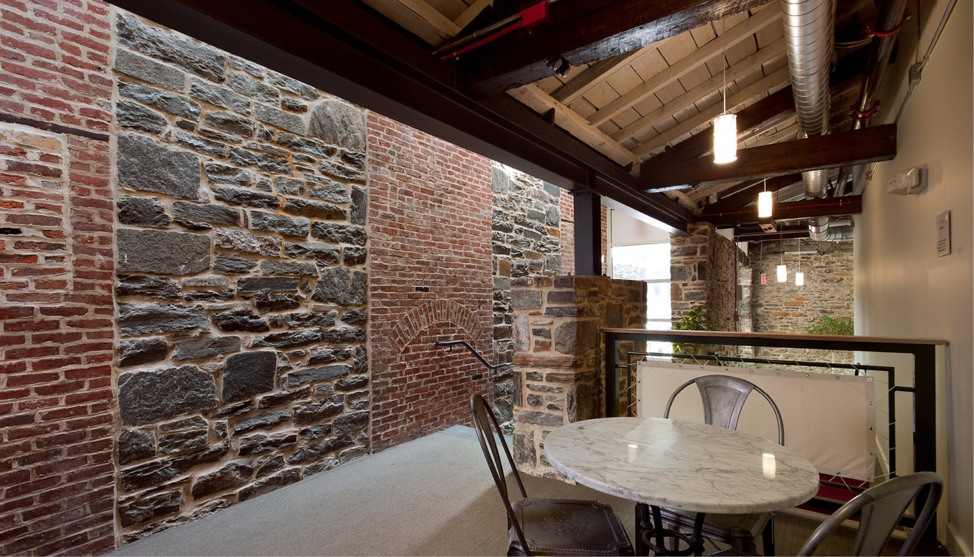 A room with a table and chairs, adorned with Artifact Coffee's signature charm, nestled within the historic Union Mill's stone wall.