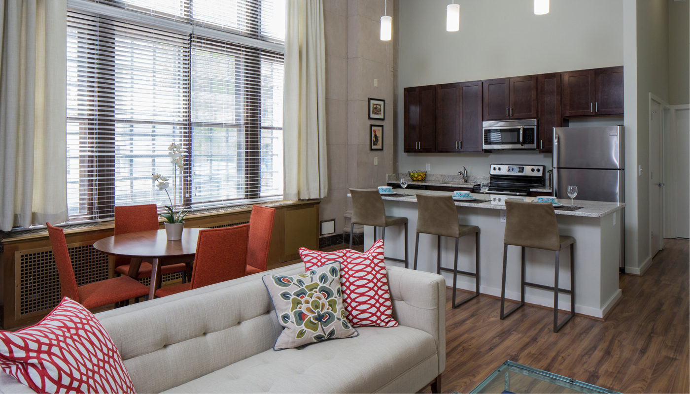 A living room, kitchen, and dining area in a small apartment featuring Lenore's artistic touch.