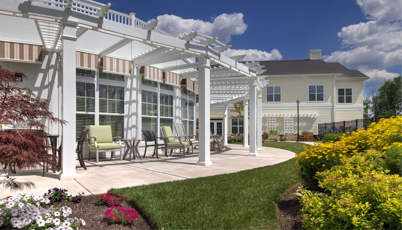 A patio with a Warwick pergola and Bridges flowers.