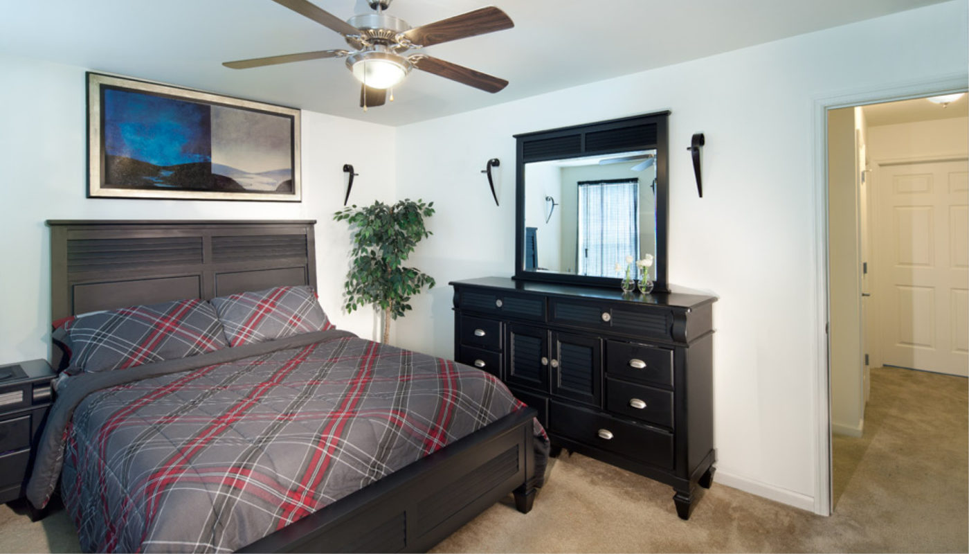 A Key's Pointe bedroom with a bed, dresser and ceiling fan.