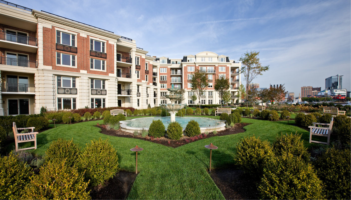 The Ritz-Carlton Residences, an elegant apartment building, features a serene fountain on a lush lawn.