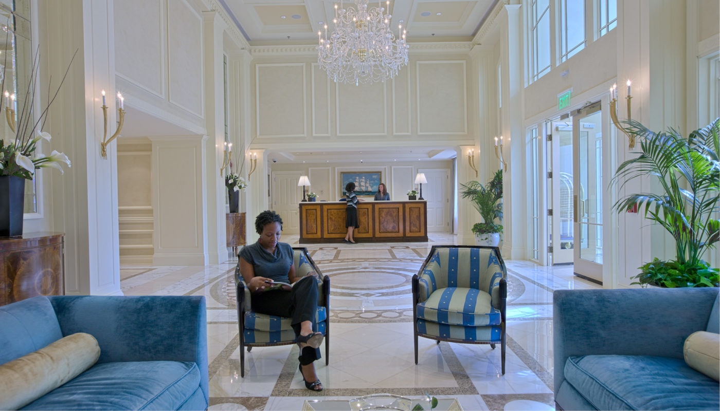 A woman sits in a blue chair in the lobby of the Ritz-Carlton Residences.