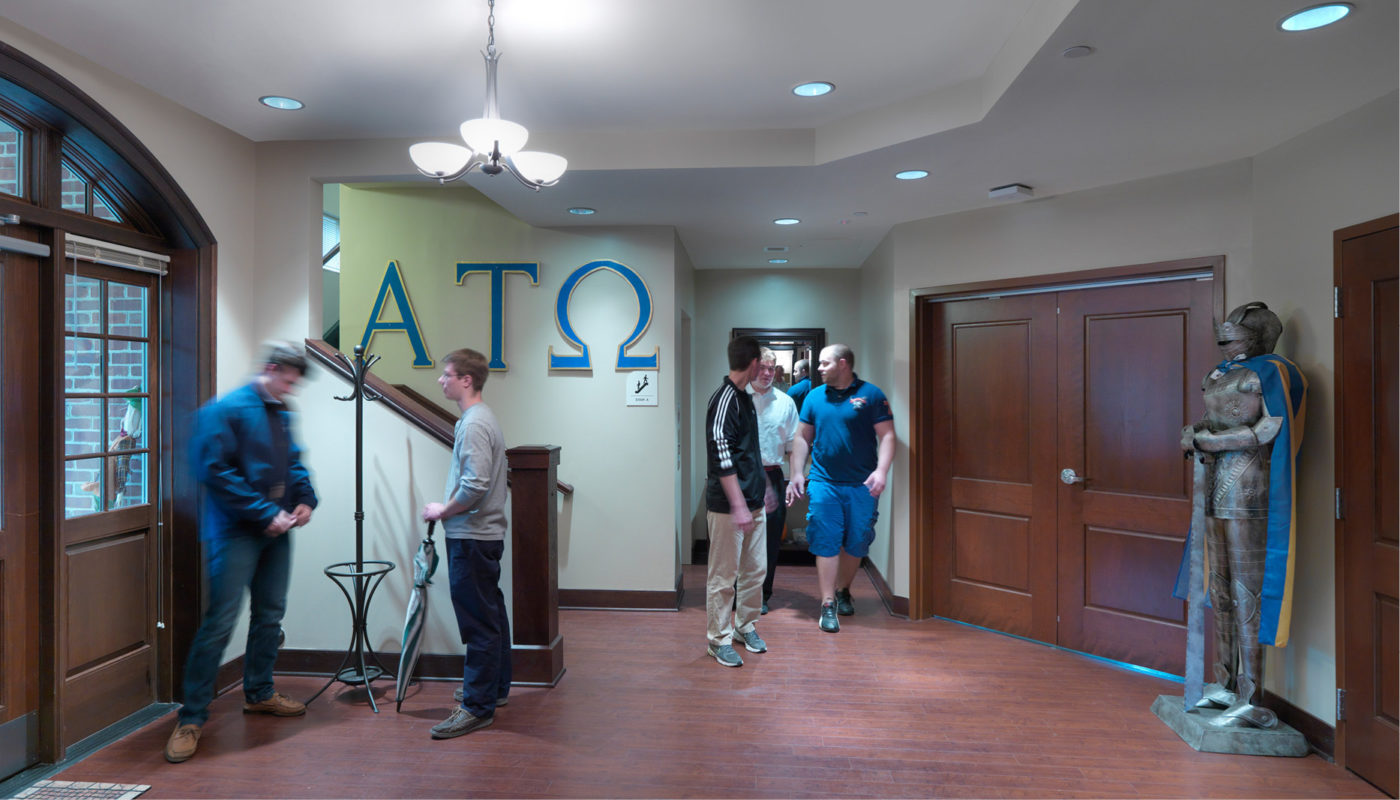 A group of Greek students from the College of William and Mary standing in a fraternity housing hallway.