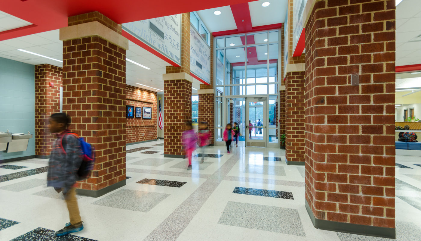 A school hallway in Chris Yung Elementary School with children walking down the hallway.