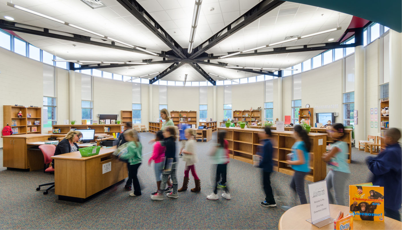 Students from Chris Yung Elementary School, part of Prince William County Public Schools, are walking around in a library.