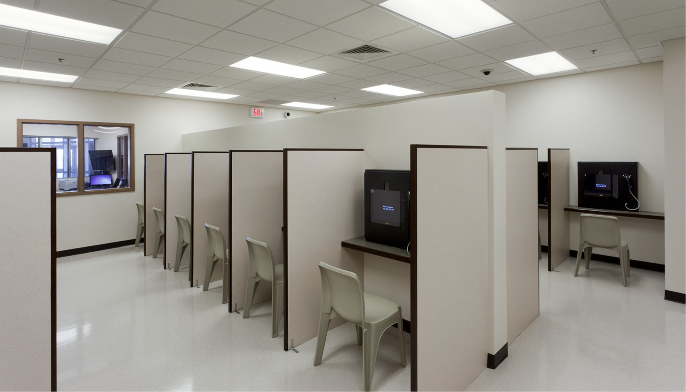 Guilford County Detention Center – A room with several desks and chairs in it.