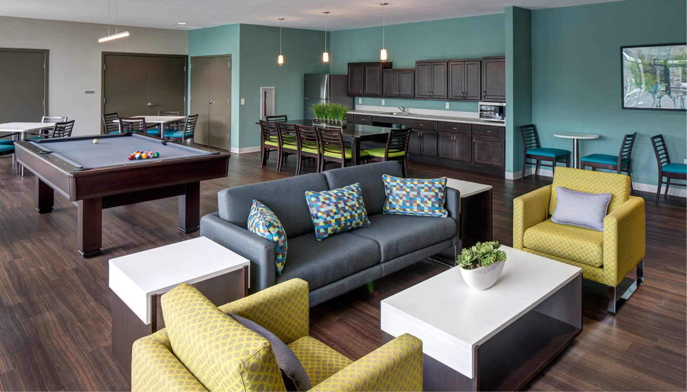 A living room at Gibbons Apartments with a pool table and couches.