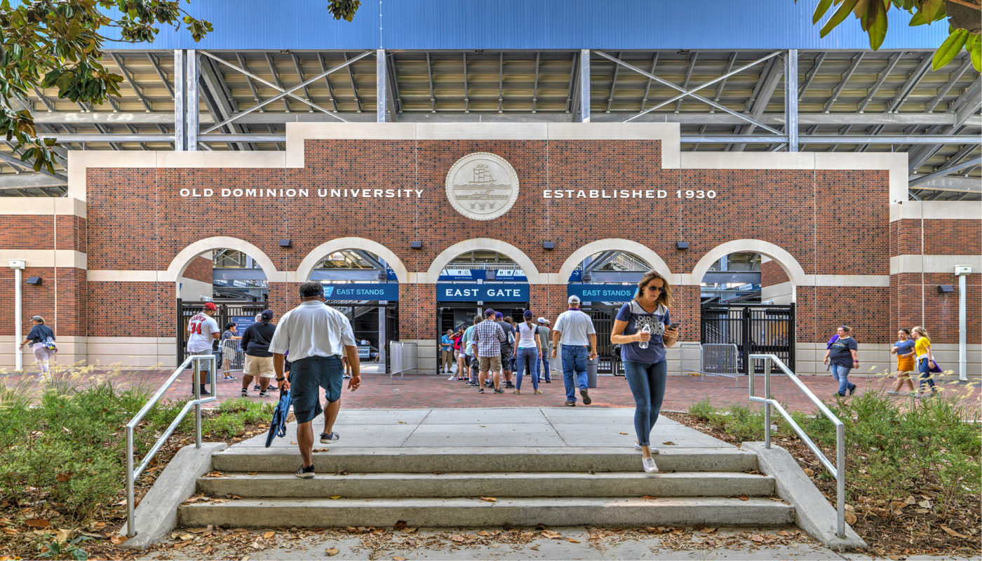 A group of people walking to the entrance of Kornblau Field at Old Dominion University.