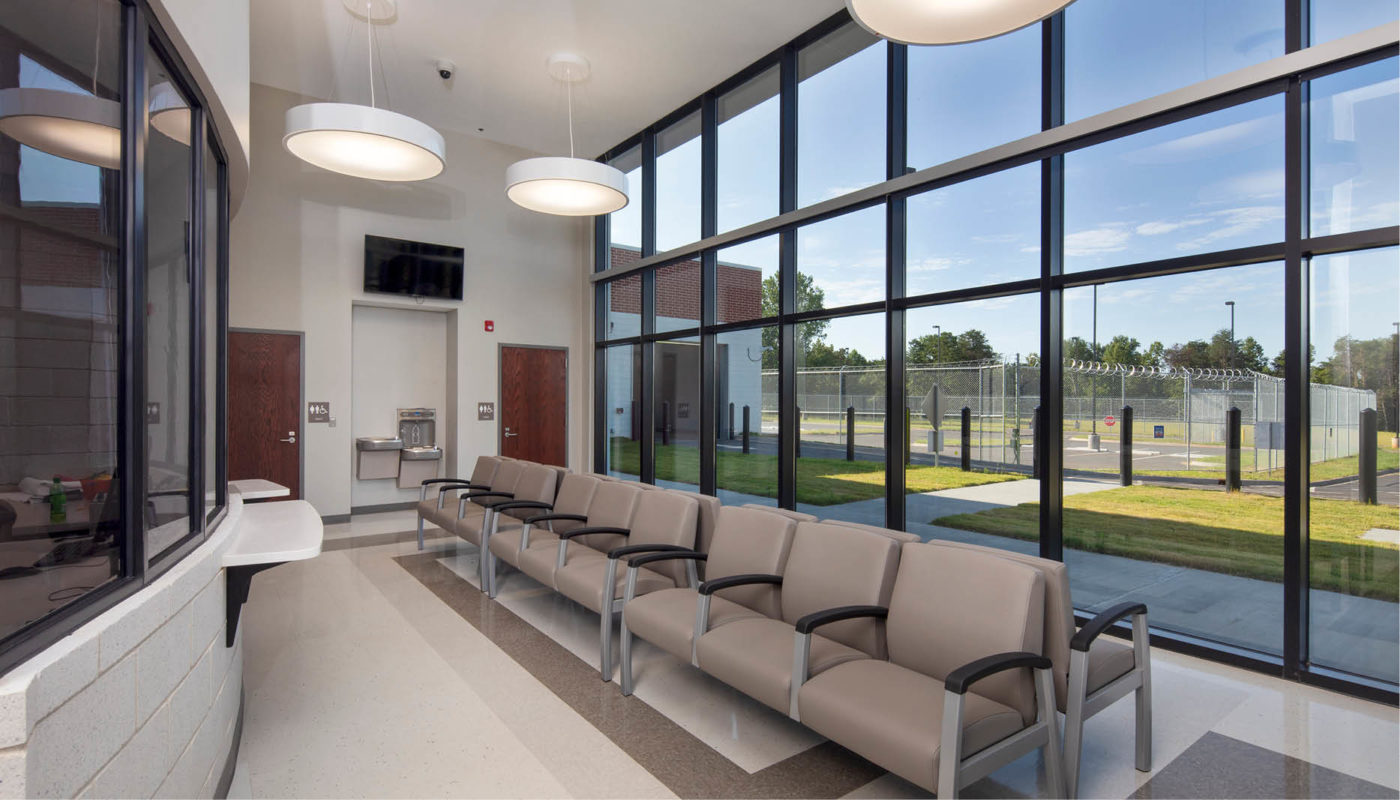 The Pickens County Detention Center features a spacious waiting room adorned with large windows and comfortable chairs.