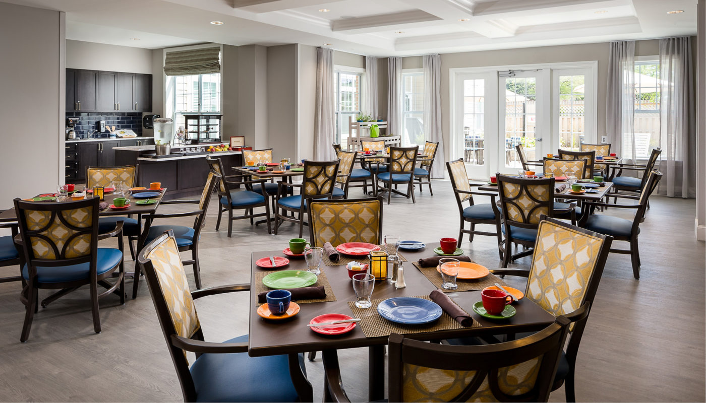 A dining room with tables and chairs located in the Atria Glenview.