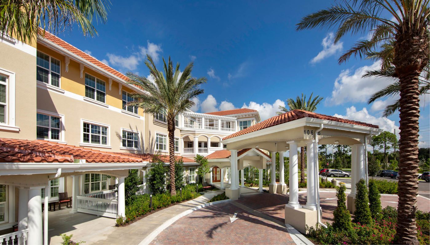 The serene entrance to a Boynton Beach retirement community lined with palm trees.
