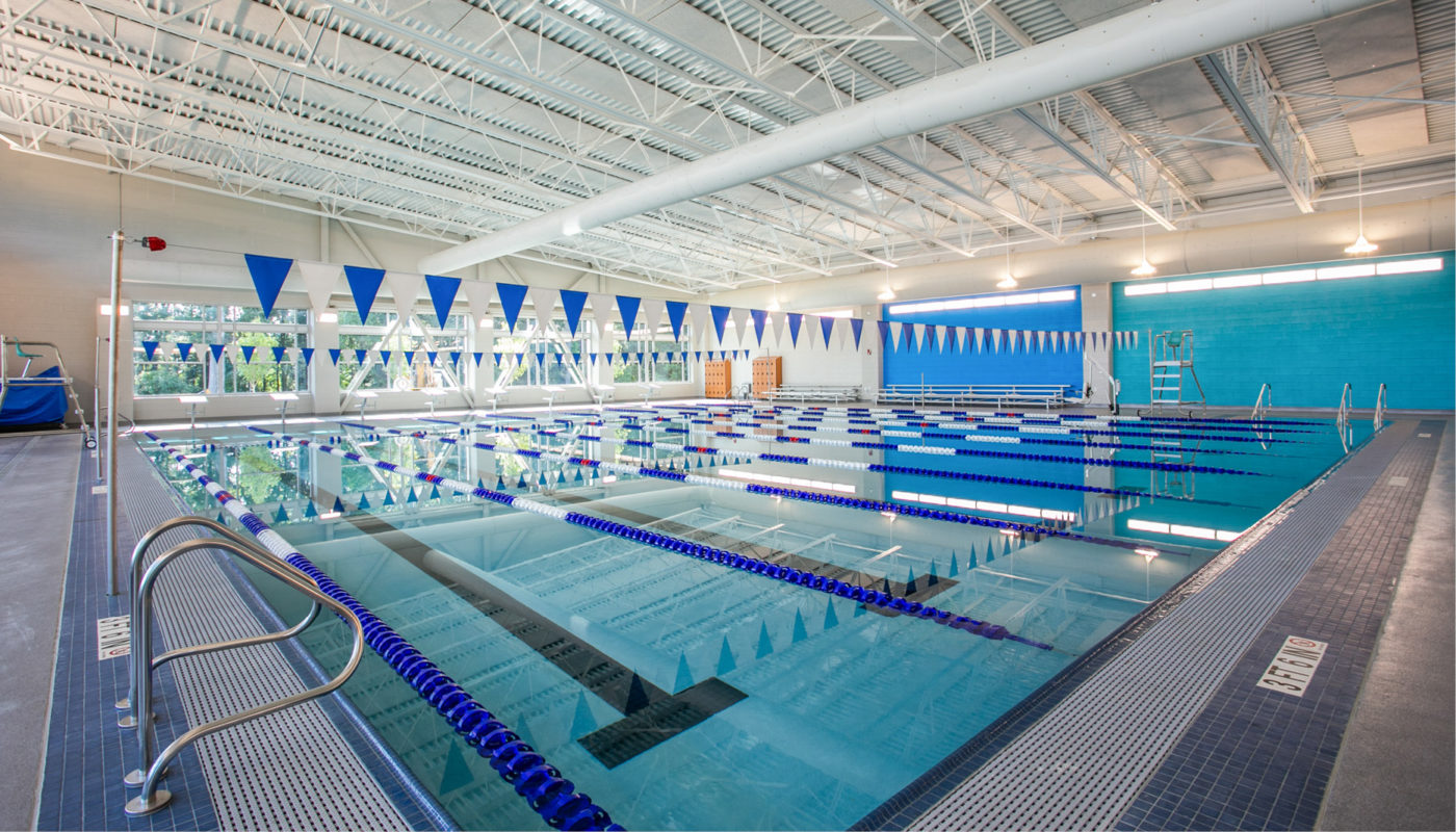 The Frank J. Thornton YMCA Aquatic Center boasts a large indoor swimming pool adorned with blue flags.