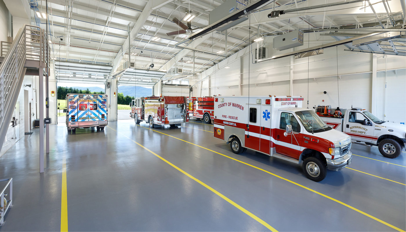 Emergency vehicles are parked in a fire station building.