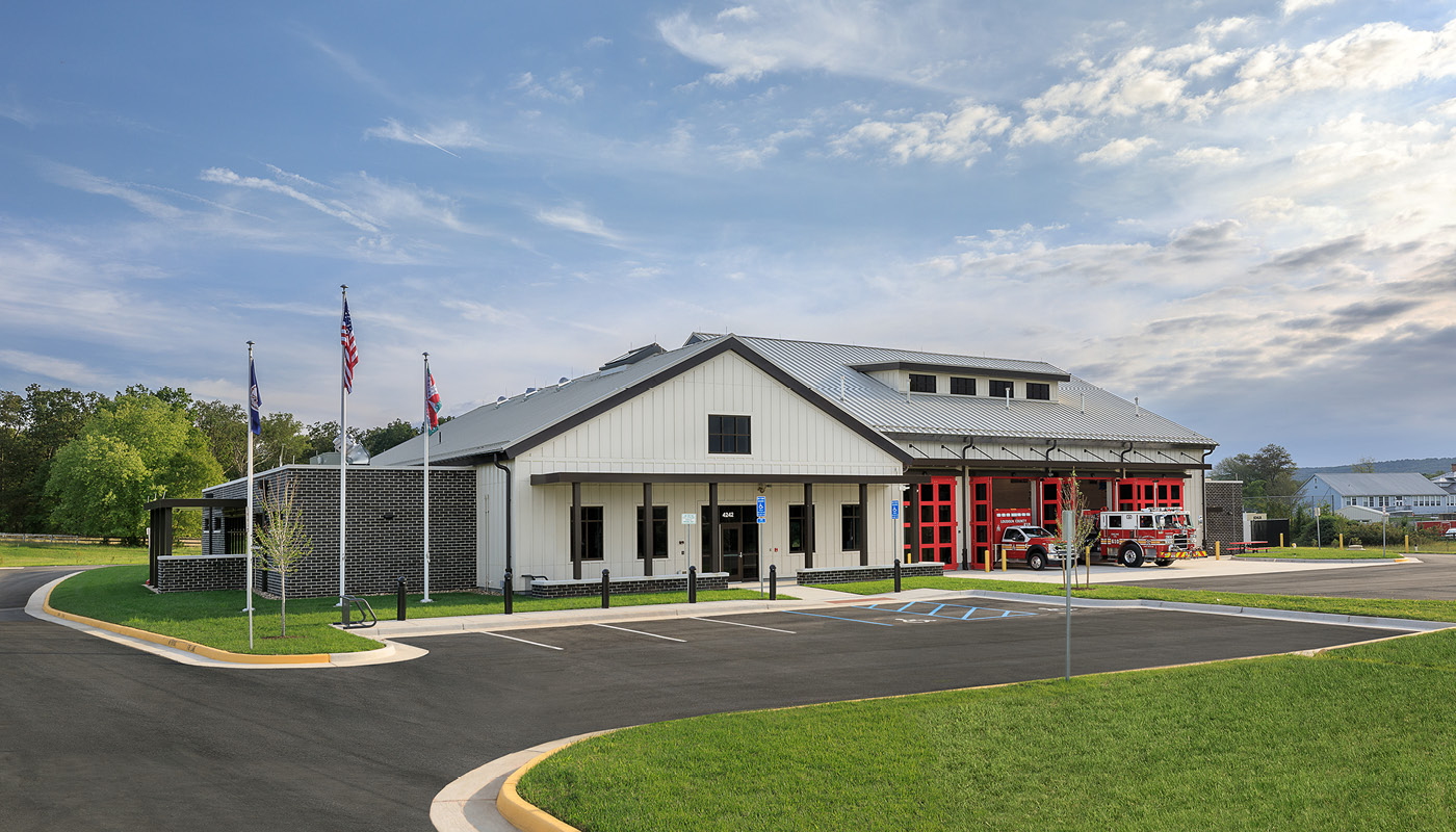A rural fire station with a large white building and flags.