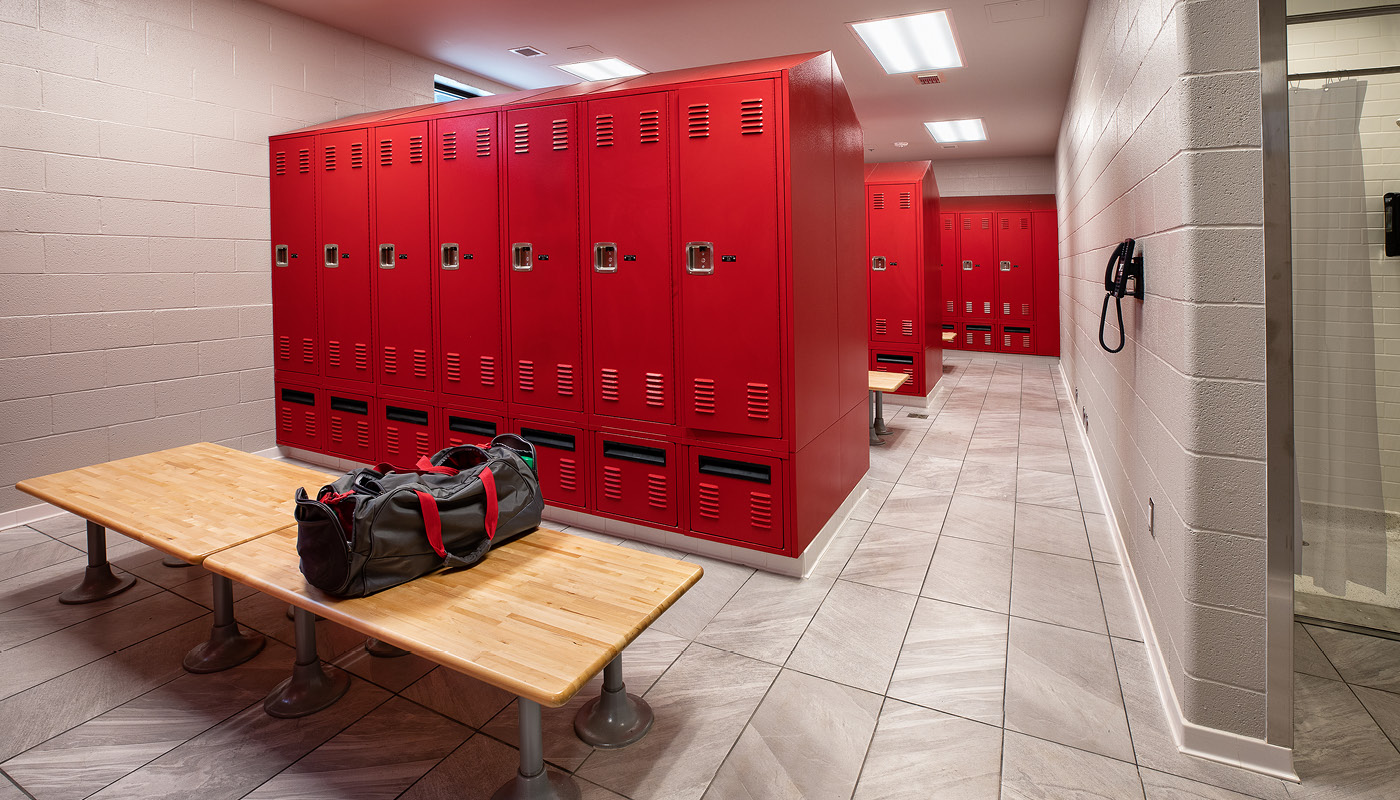 A locker room with red lockers and a bench in a fire station.