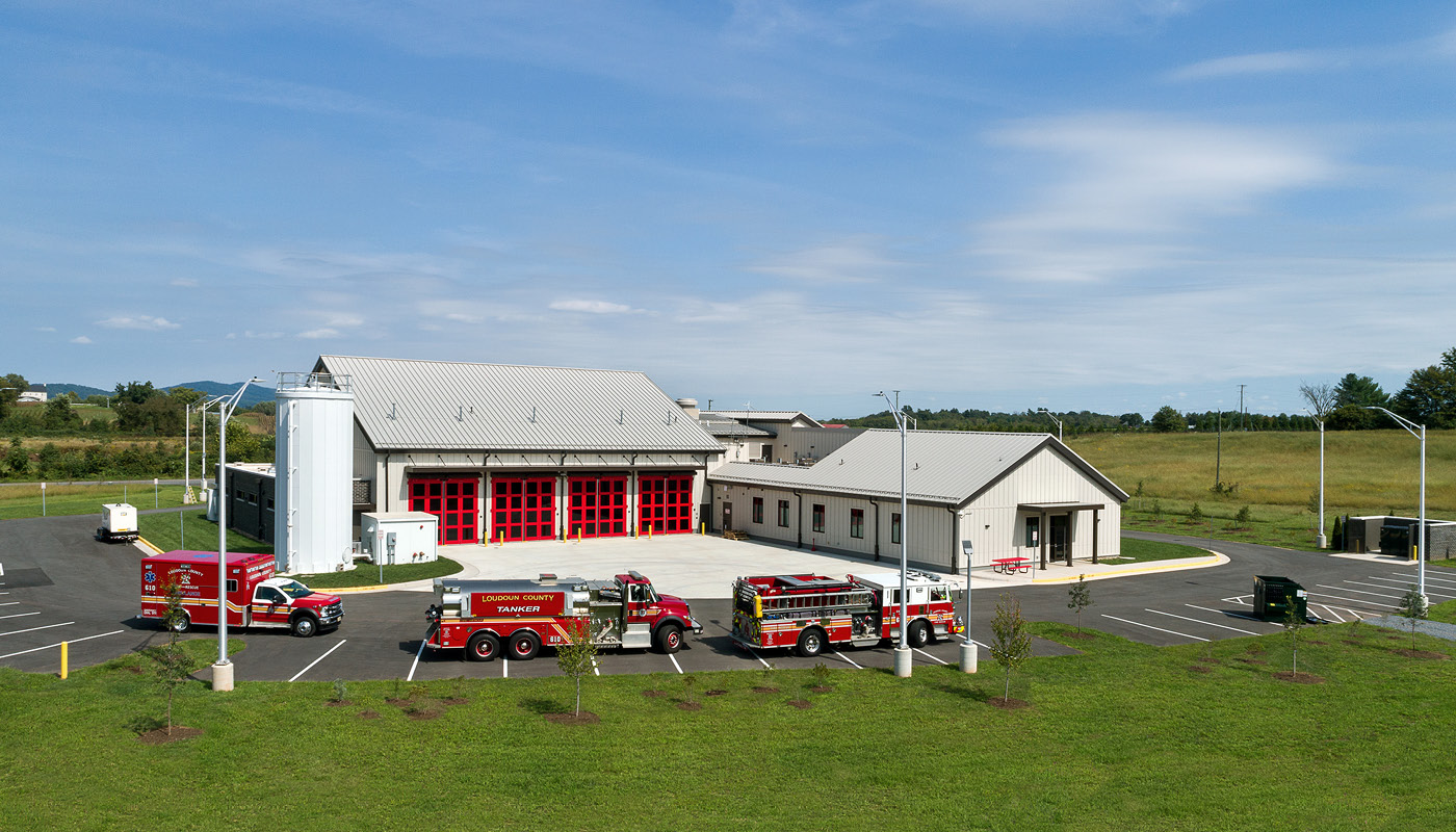 A fire truck parked in front of a rural fire station.