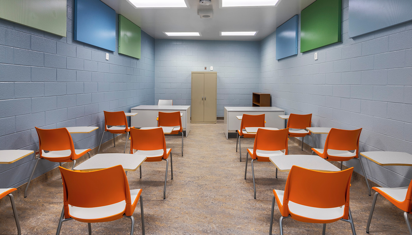A room full of orange chairs in a juvenile detention center.